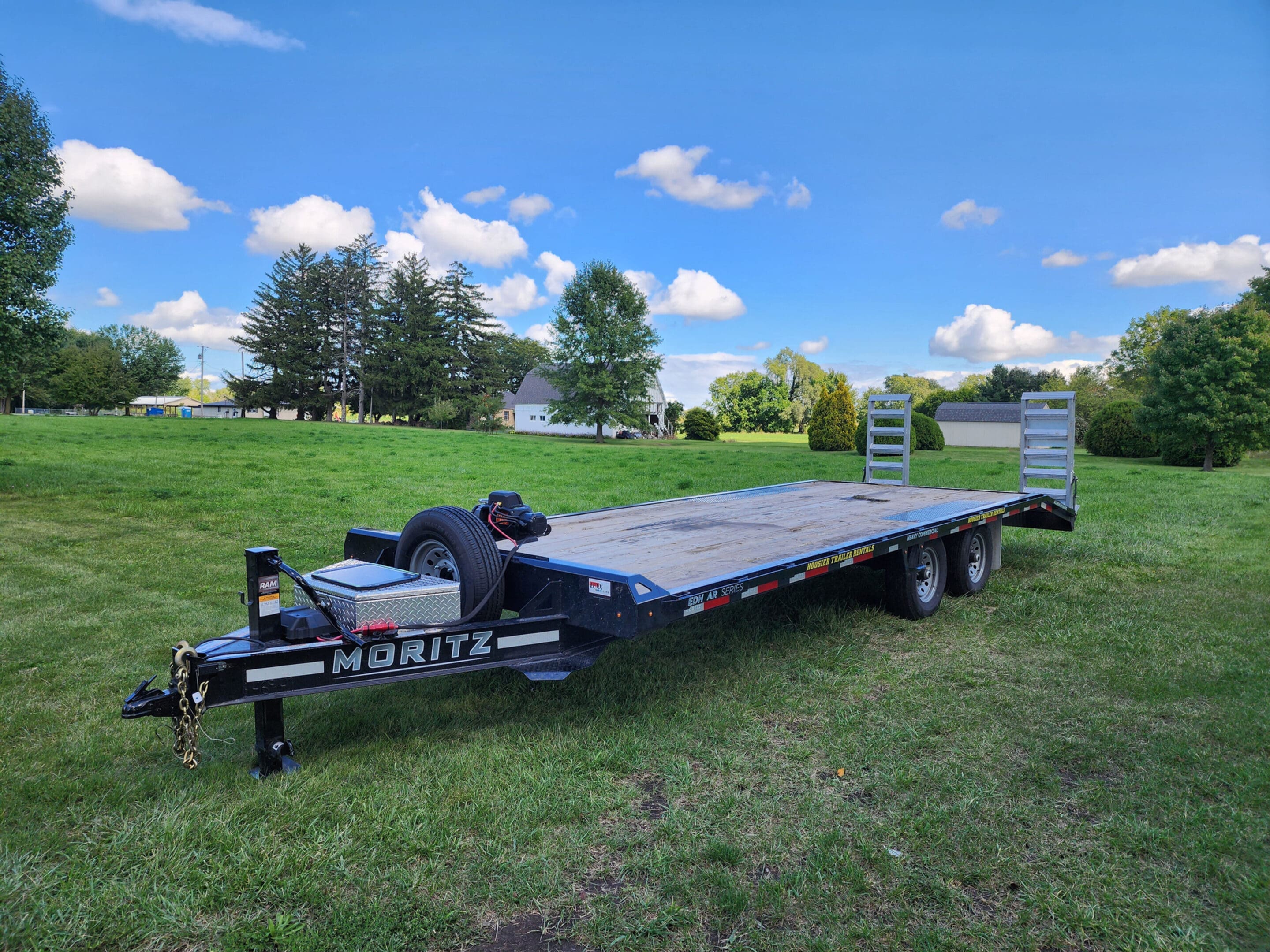 A large trailer is parked in the grass.
