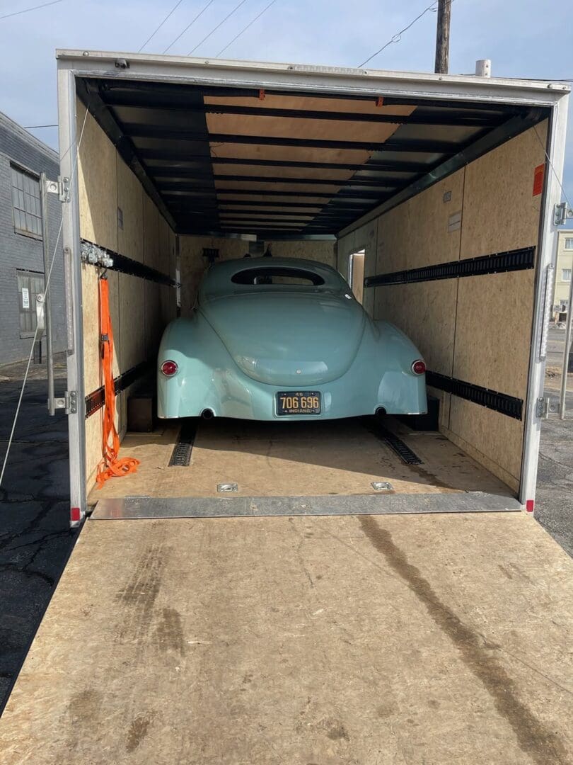 A blue car is in the back of a truck.